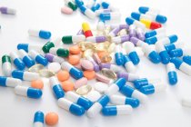 Scattered pills on white surface — Stock Photo