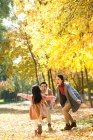 Happy asian daughter running to parents in autumnal park — Stock Photo