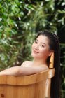 Красива азіатська жінка лежить у дерев'яній ванні в саду — стокове фото