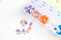 Top view of pills in daily container on white surface — Stock Photo