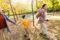 Щаслива молода азіатська сім'я ходить разом в осінньому лісі — стокове фото