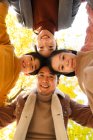 Inferior vista de feliz joven asiático familia con dos niños de pie juntos y sonriendo a la cámara en otoño bosque - foto de stock