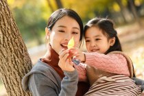 Felice asiatico madre e figlia guardando autunno foglia in parco — Foto stock