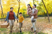 Felice giovane famiglia asiatica con cestino da picnic a piedi nel parco autunnale — Foto stock