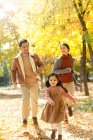 Feliz asiático padres y hija corriendo en otoñal parque - foto de stock
