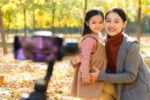 Счастливый азиатский отец фотографирует дочь и жену со смартфоном в осеннем парке — стоковое фото