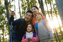 Happy family with backpacks trekking and looking away together in autumn forest — Stock Photo