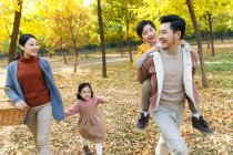 Щасливі молоді батьки з двома чарівними дітьми ходять разом в осінньому парку — стокове фото