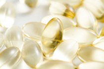 Closeup of scattered yellow pills on white surface — Stock Photo