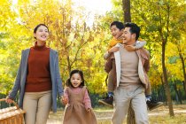 Glückliche junge asiatische Familie mit Picknickkorb wandern im herbstlichen Park — Stockfoto
