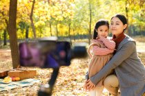 Felice padre asiatico scattare foto di figlia e moglie con smartphone nel parco autunnale — Foto stock