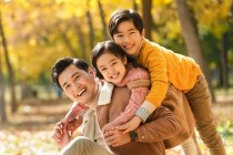 Счастливый отец с детьми развлекается в осеннем парке — стоковое фото