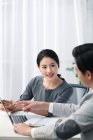 Asiático hombre de negocios y mujer de negocios apuntando en portátil en la oficina de luz - foto de stock