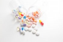 Разбросанные таблетки из банок на белой поверхности — стоковое фото