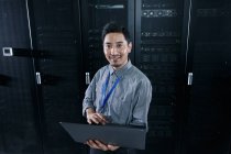 Технічний персонал, який використовує комп'ютер і посміхається на камеру в кабінеті технічного обслуговування — стокове фото