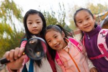 Tre adorabile asiatico bambini abbraccio e guardando lente di ingrandimento in autunno parco — Foto stock
