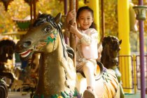 Entzückend glückliches kleines Mädchen, das mit Karussell spielt und in die Kamera lächelt — Stockfoto