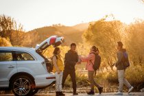 Мужчины и женщины азиатские друзья берут вещи для пикника из автомобиля в осеннем лесу — стоковое фото