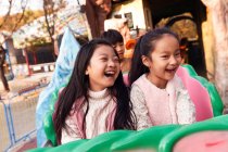 Feliz asiático niños sentado juntos en rodillo montaña rusa en parque - foto de stock