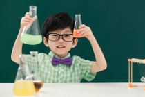 Entzückender asiatischer Schüler mit Glühbirnen im Chemieunterricht in der Schule — Stockfoto