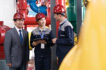 Ingenieros chinos en sombreros duros trabajando juntos en la inspección de fábrica - foto de stock