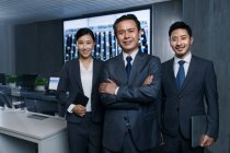 Professional business people smiling at camera while working together in the control room — Stock Photo