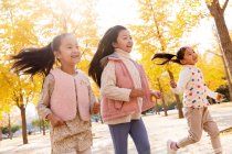 Três adorável feliz asiático crianças correndo no outonal parque — Fotografia de Stock