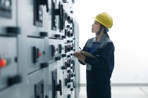 Technikerin mit gelbem Helm arbeitet in Fabrik — Stockfoto