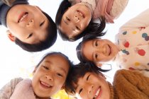 Low angle view of five adorable smiling asian kids looking at camera in autumnal park — Stock Photo