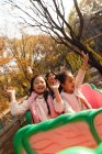 Felici bambini asiatici seduti insieme sulle montagne russe nel parco — Foto stock