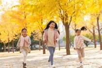 Drei entzückende glückliche asiatische Kinder laufen im herbstlichen Park — Stockfoto