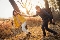 Asiatisches Paar hält Händchen und wandert im herbstlichen Wald — Stockfoto