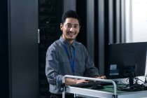 Технічний персонал, який використовує комп'ютер і посміхається на камеру в кабінеті технічного обслуговування — стокове фото