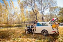 Asiatische Freunde sitzen im Auto im herbstlichen Wald — Stockfoto