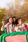 Ragazzo felice e ragazze che giocano insieme sulle montagne russe nel parco — Foto stock