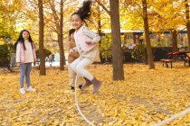 Счастливые мальчик и девочка играют вместе и прыгают в осеннем парке — стоковое фото