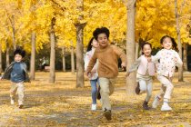 Five adorable asian kids running in autumnal park — Stock Photo