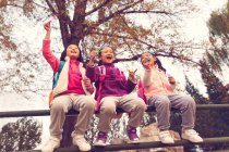 Bajo ángulo vista de tres adorable asiático niños soplando jabón burbujas en otoñal parque - foto de stock