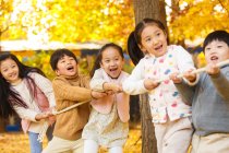 П'ять чарівних щасливих азіатських дітей тягнуть мотузку разом в автономному парку — стокове фото