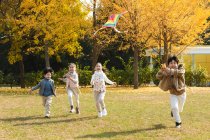 Happy boys and girls playing together with kite in park — Stock Photo