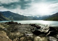 Amazing mountain landscape with lake and clouds in sky — Stock Photo