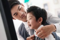 Selective focus of cheerful asian father wearing son at home — Stock Photo
