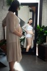 Vista laterale di felice giovane donna asiatica incinta guardando specchio — Foto stock