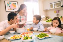 Glückliche asiatische Familie mit zwei Kindern beim gemeinsamen Abendessen zu Hause — Stockfoto