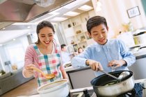 Happy asian mother with son cooking together in kitchen — Stock Photo