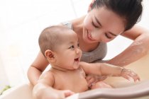 Felice giovane madre che fa il bagno adorabile bambino a casa — Foto stock