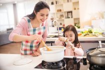 Heureux asiatique mère et fille cuisson soupe ensemble dans cuisine — Photo de stock