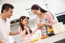Glückliche asiatische Familie mit einem Kind, das gemeinsam in der Küche kocht — Stockfoto