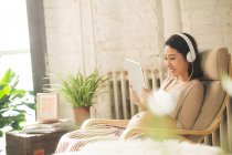Sorrindo jovem grávida em fones de ouvido usando tablet digital em casa — Fotografia de Stock