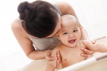 Giovane madre baciare e fare il bagno adorabile bambino infante felice — Foto stock